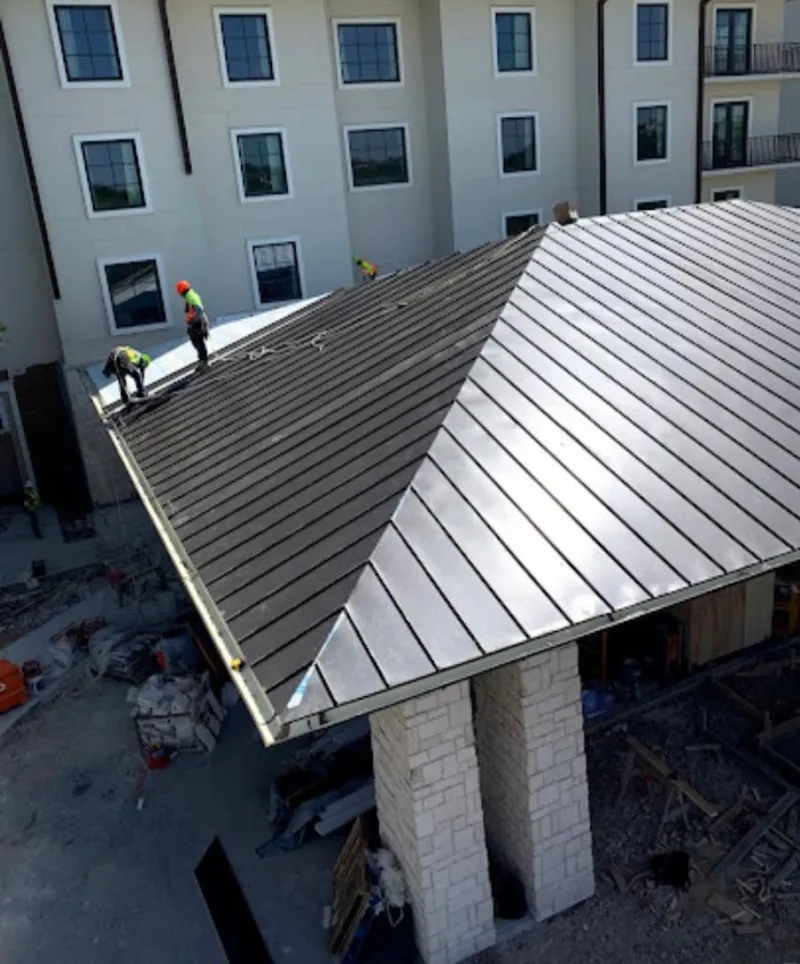 Crew installing standing seam metal roof panels on a commercial project in Monticello